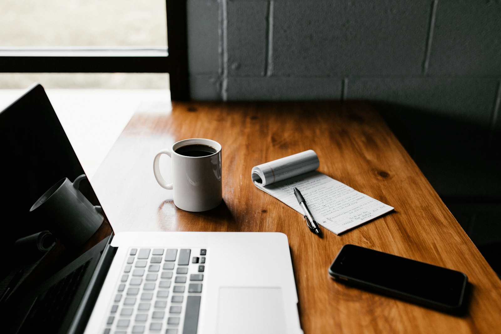 A quiet desk in the morning: coffee, a notebook, and a phone