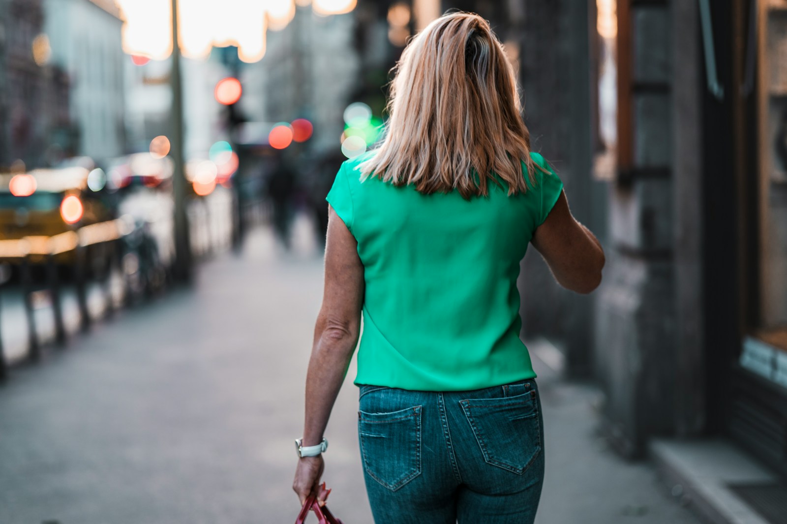 A woman walking through the city at dusk, phone to her ear